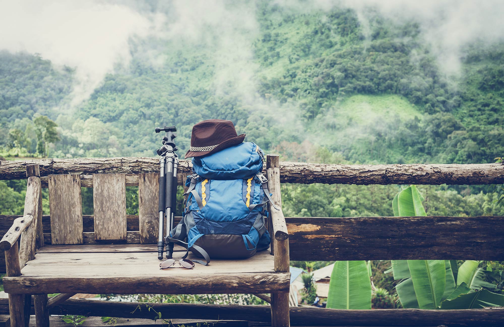 Backpack and travel gear on a wooden bench in a tropical location