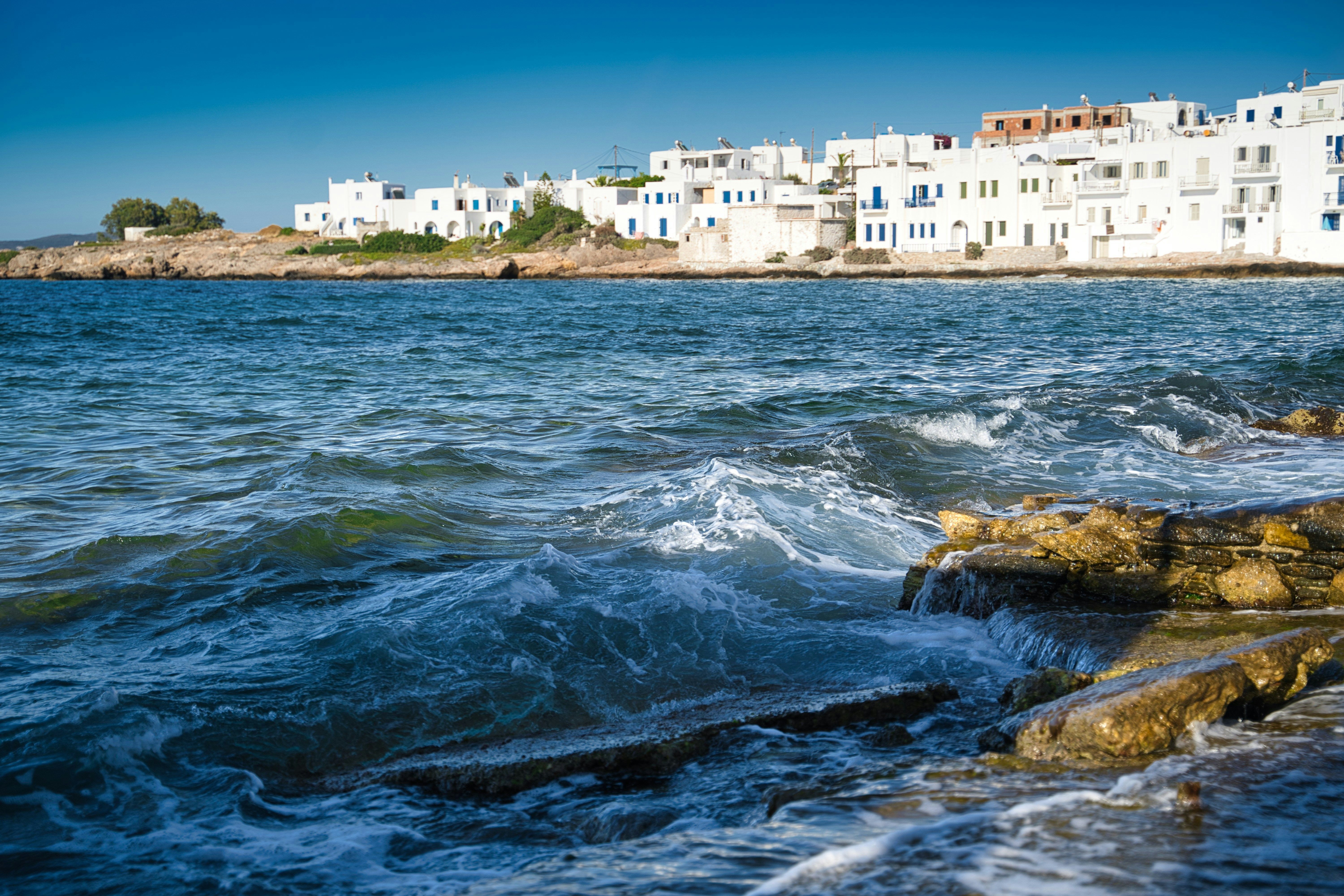 Image of the shoreline of a white-washed town on the island of Paros in Greece - KILROY