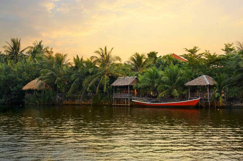 Boats and huts on a river bank in the Kampot province in Southern Cambodia
