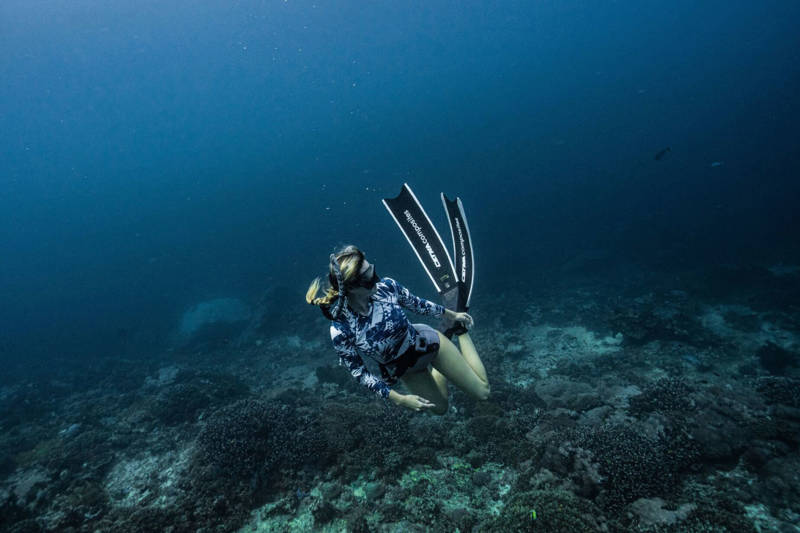 Girl with blonde hair freediving in the ocean around Bali in Indonesia