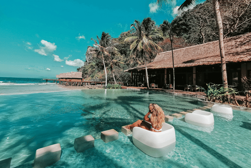 Girl sitting in the water at a beach hotel in Palawan in the Philippines
