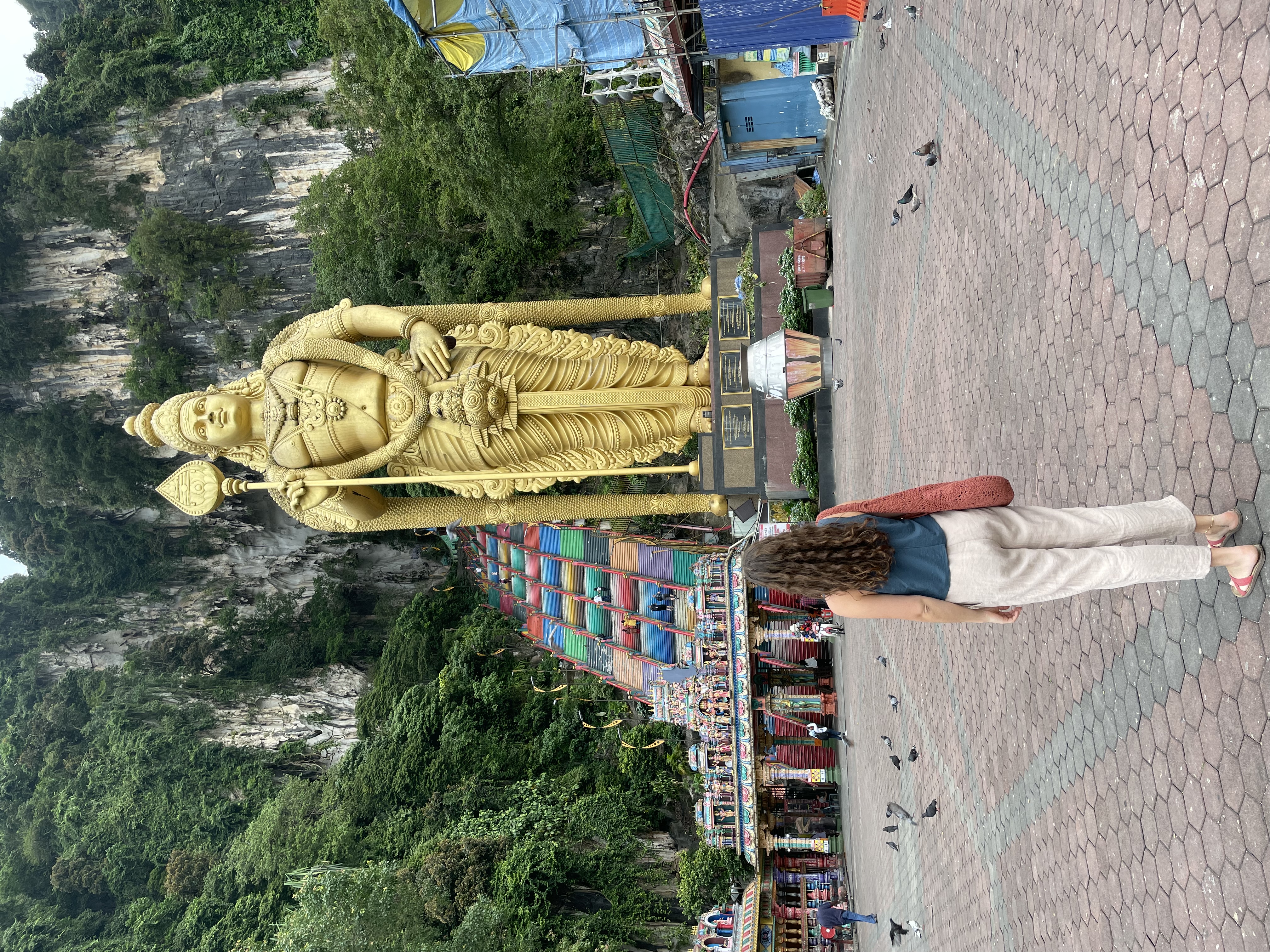 Image of a young female traveller in front of the colourful temple leading to the Batu Caves in Malaysia - KILROY