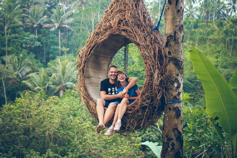Image of a couple in a wooden swing on the island of Bali - KILROY