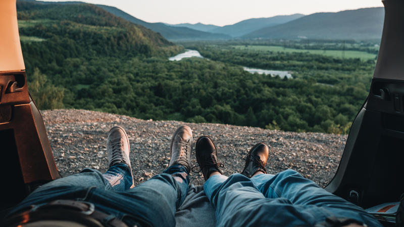Image of a couple with legs hanging out of a campervan - KILROY