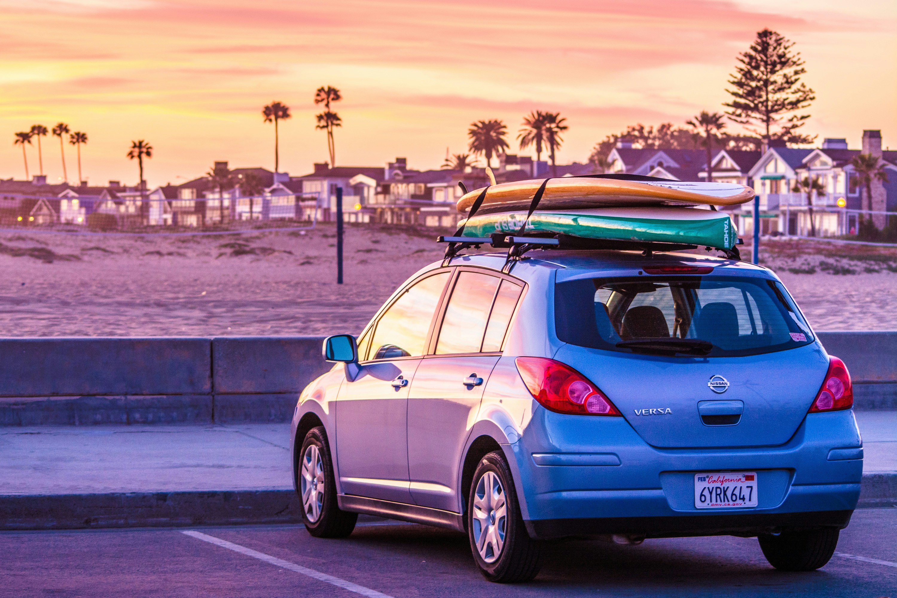 Image of a car with surfboards on the roof rack near a beach in California - KILROY