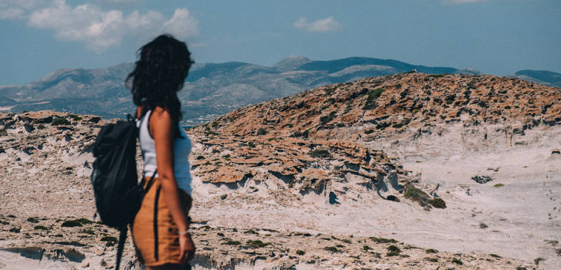Image of a female backpacker looking out at a desert landscape in Greece - KILROY