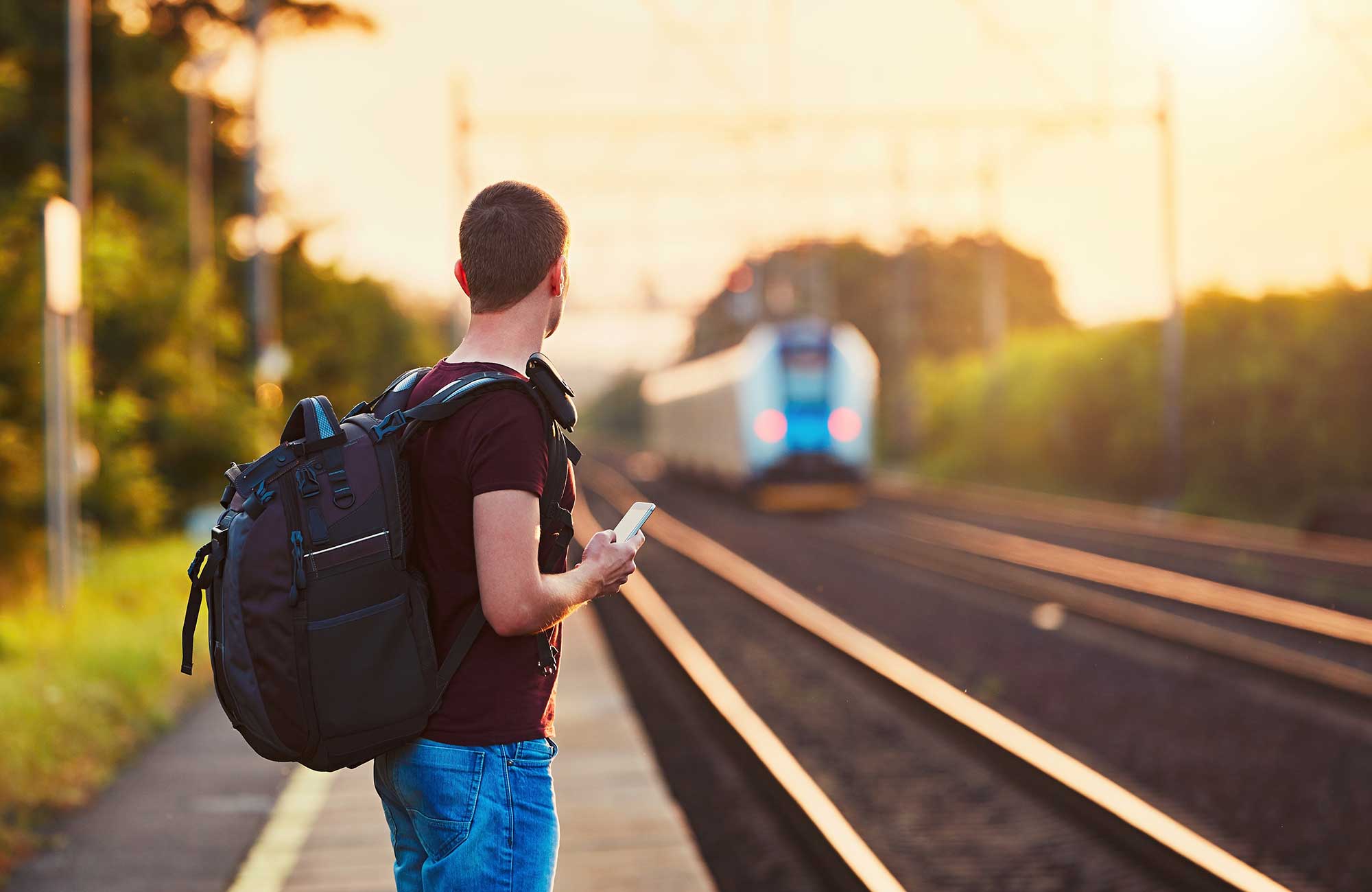 Image of a male traveller waiting for a train somewhere in Europe - KILROY