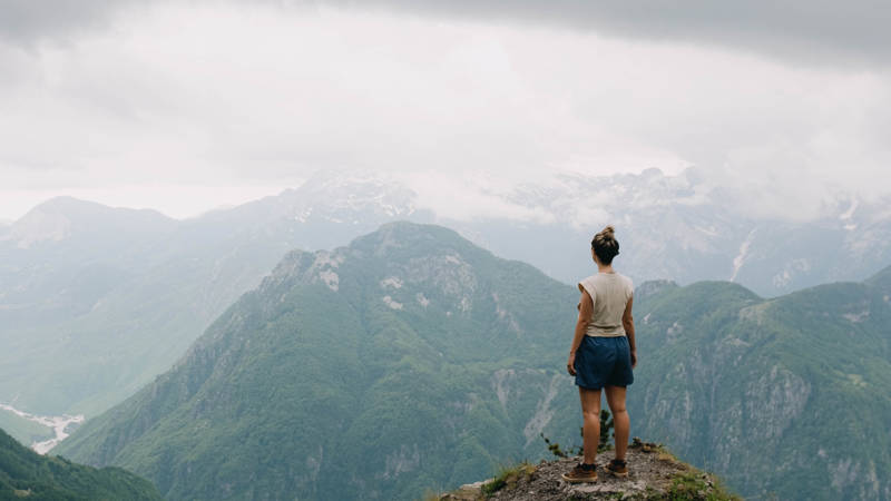 Girl standing on a mountaintop overlooking a mountainous view in the Balkans