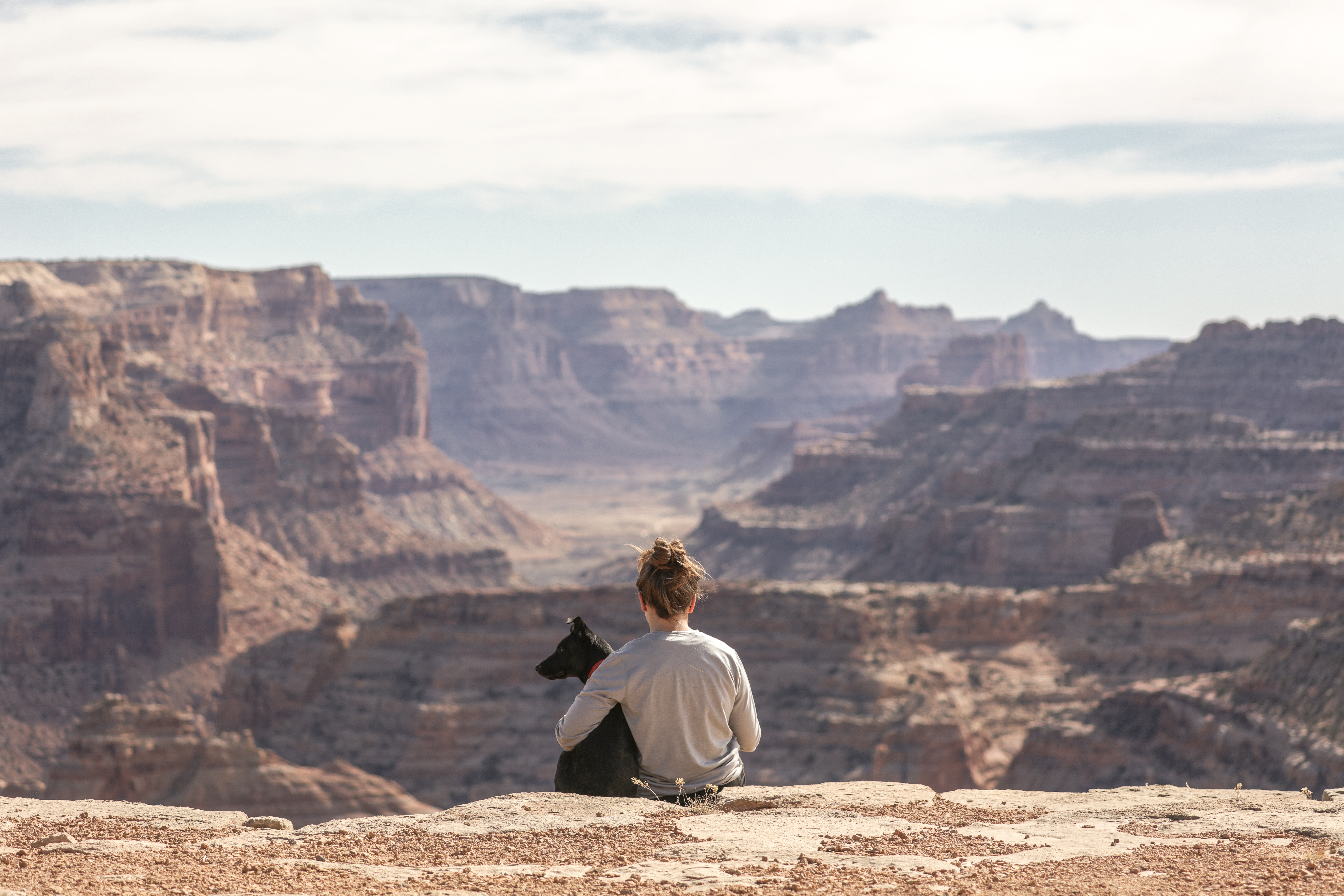 Image of a female traveller enjoying a view of a canyon with a dog sitting beside her - KILROY
