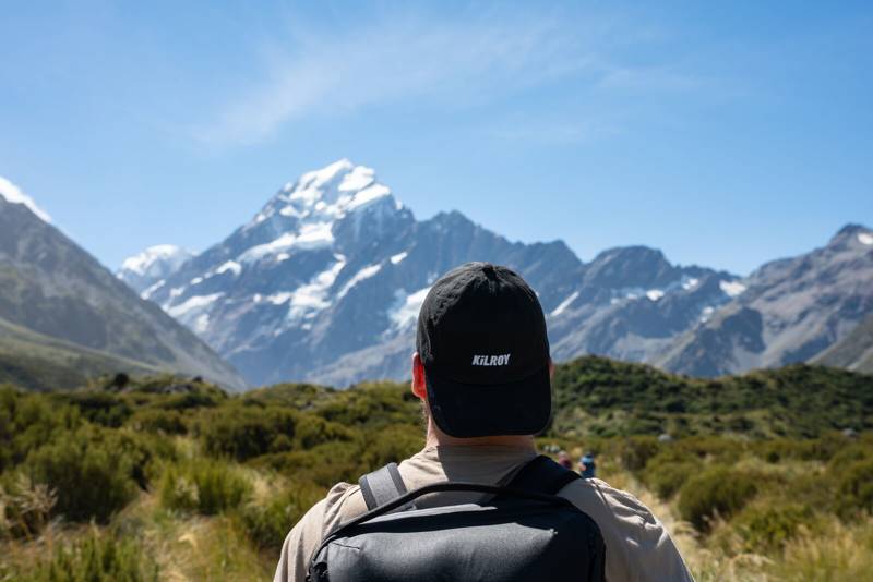 Image of a male traveller looking towards mountains somewhere in New Zealand - KILROY