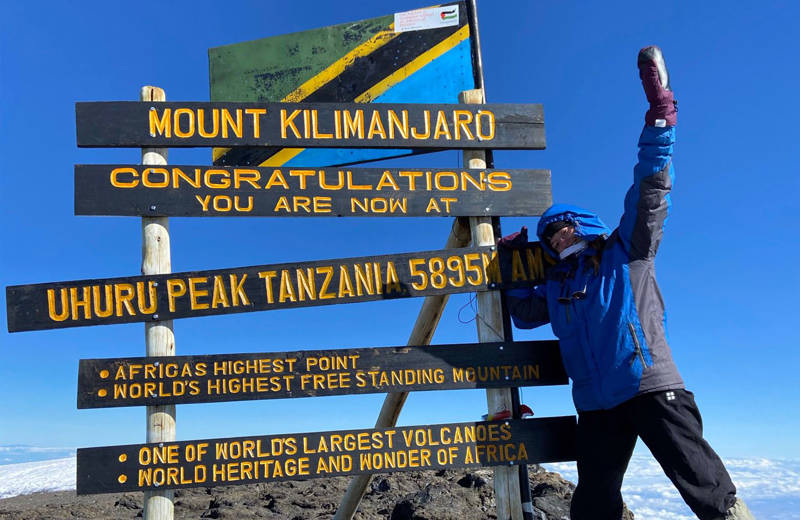 Image of a woman posing at the summit of Mt Kilimanjaro in Tanzania - KILROY