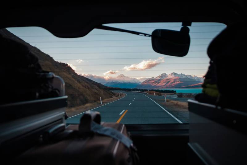 Image of a road and mountains seen through the back of a car in New Zealand - KILROY
