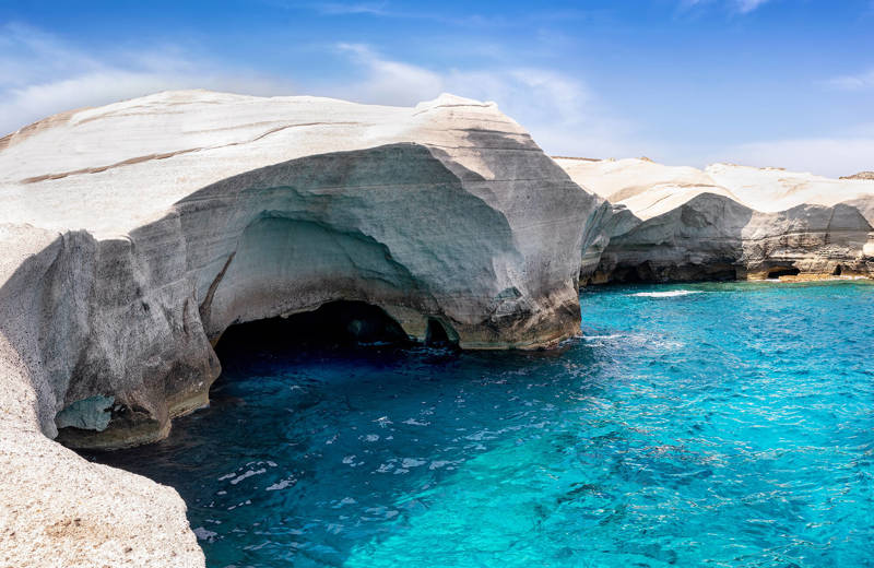 Image of a cave above bright turquoise water in Greece - KILROY