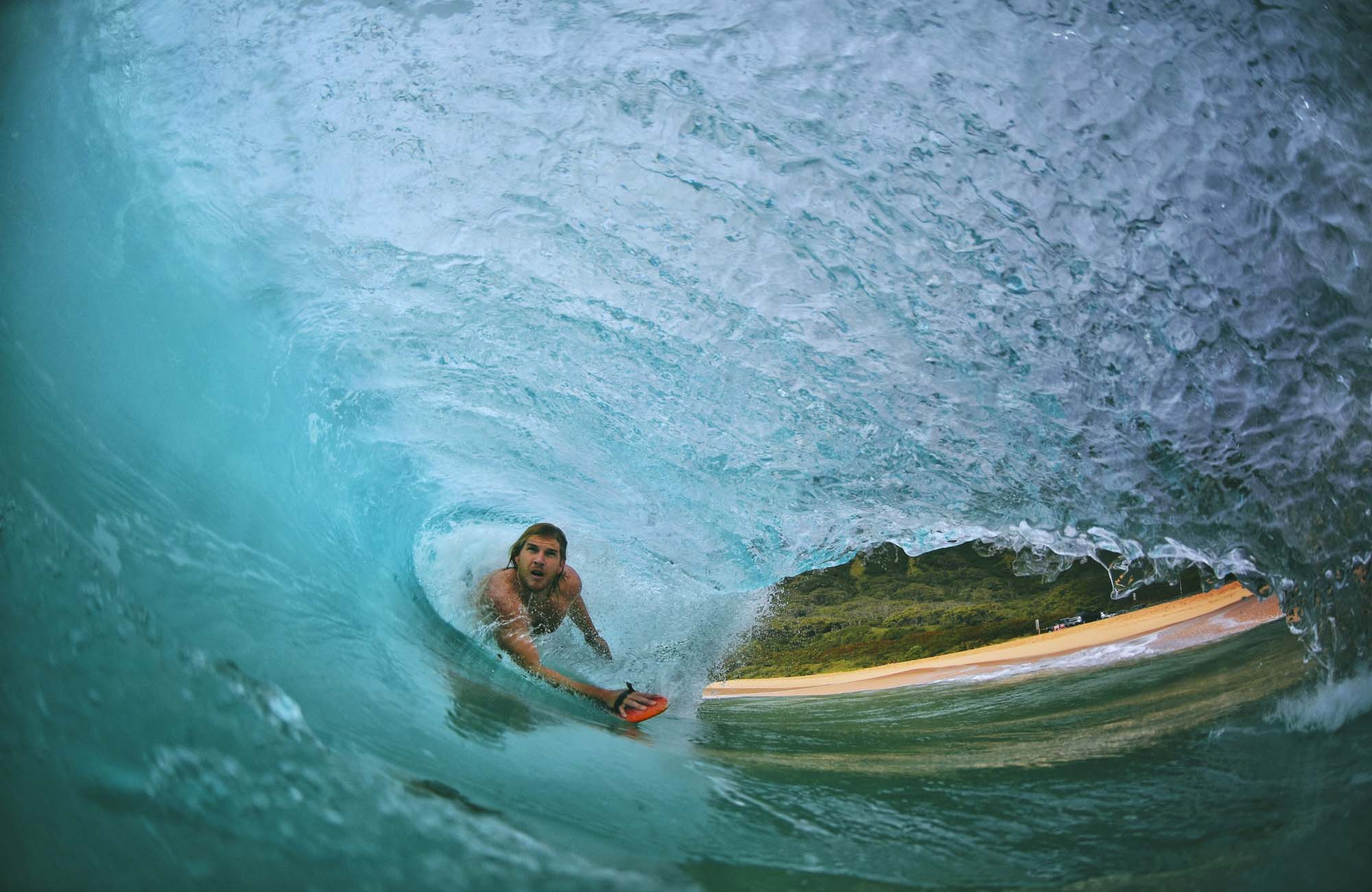 Image looking under a curling wave as a man surfs towards the camera - KILROY