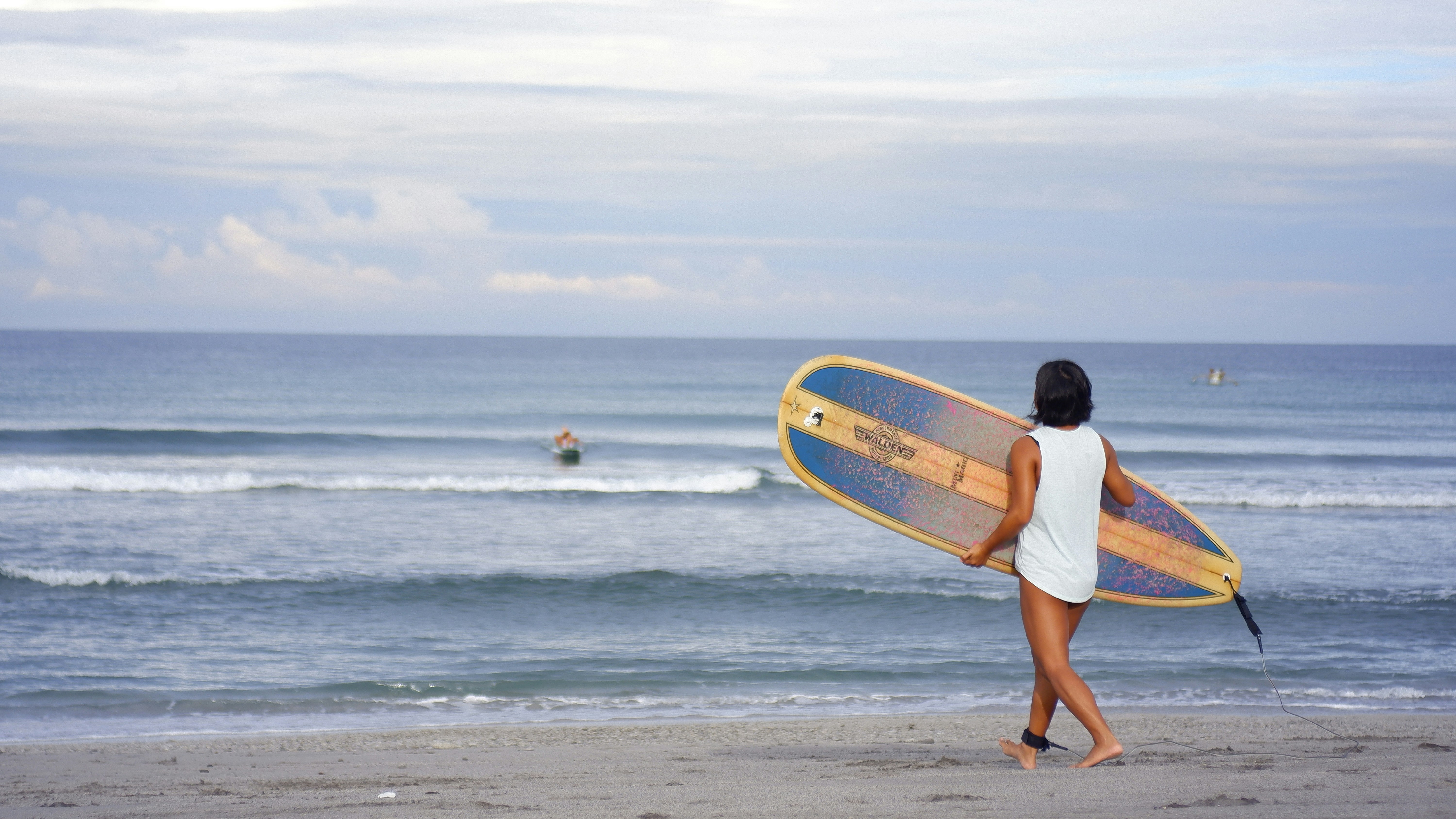 Image of a surfer with a board heading into the waters of the Philippines - KILROY