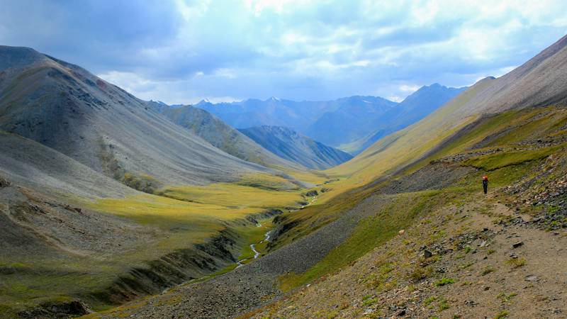 Image of a hiker on a route cutting through a valley in Kyrgyzstan - KILROY