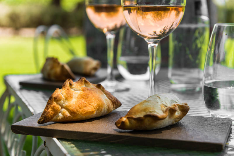 Image of empanadas and glasses of rose wine on a table at a vineyard in Mendoza, Argentina - KILROY